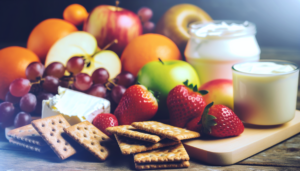 A variety of healthy snacks including fresh fruit, whole grain crackers, and dairy products