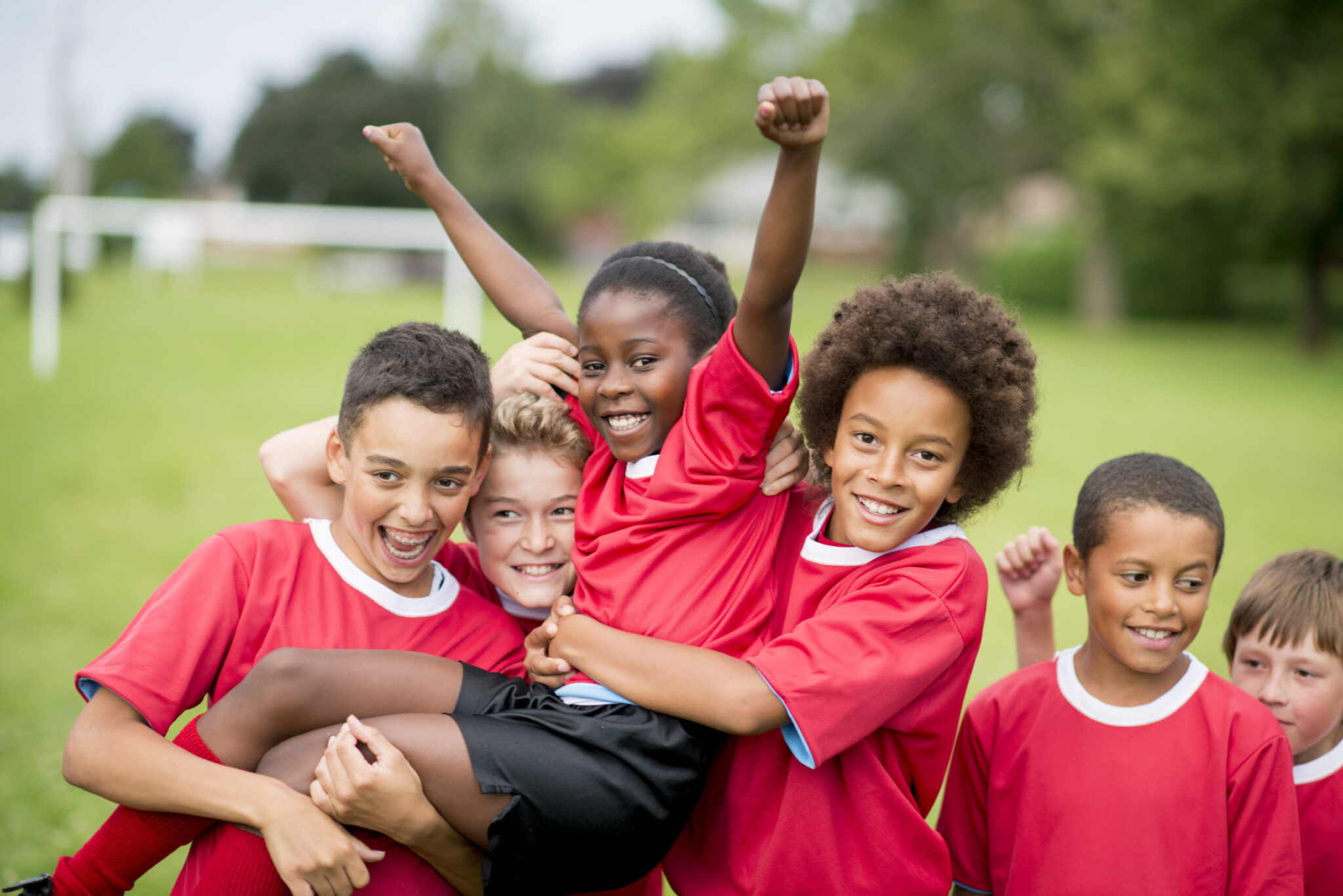 A group of children on a soccer team wearing red jerseys, celebrating their victory together.