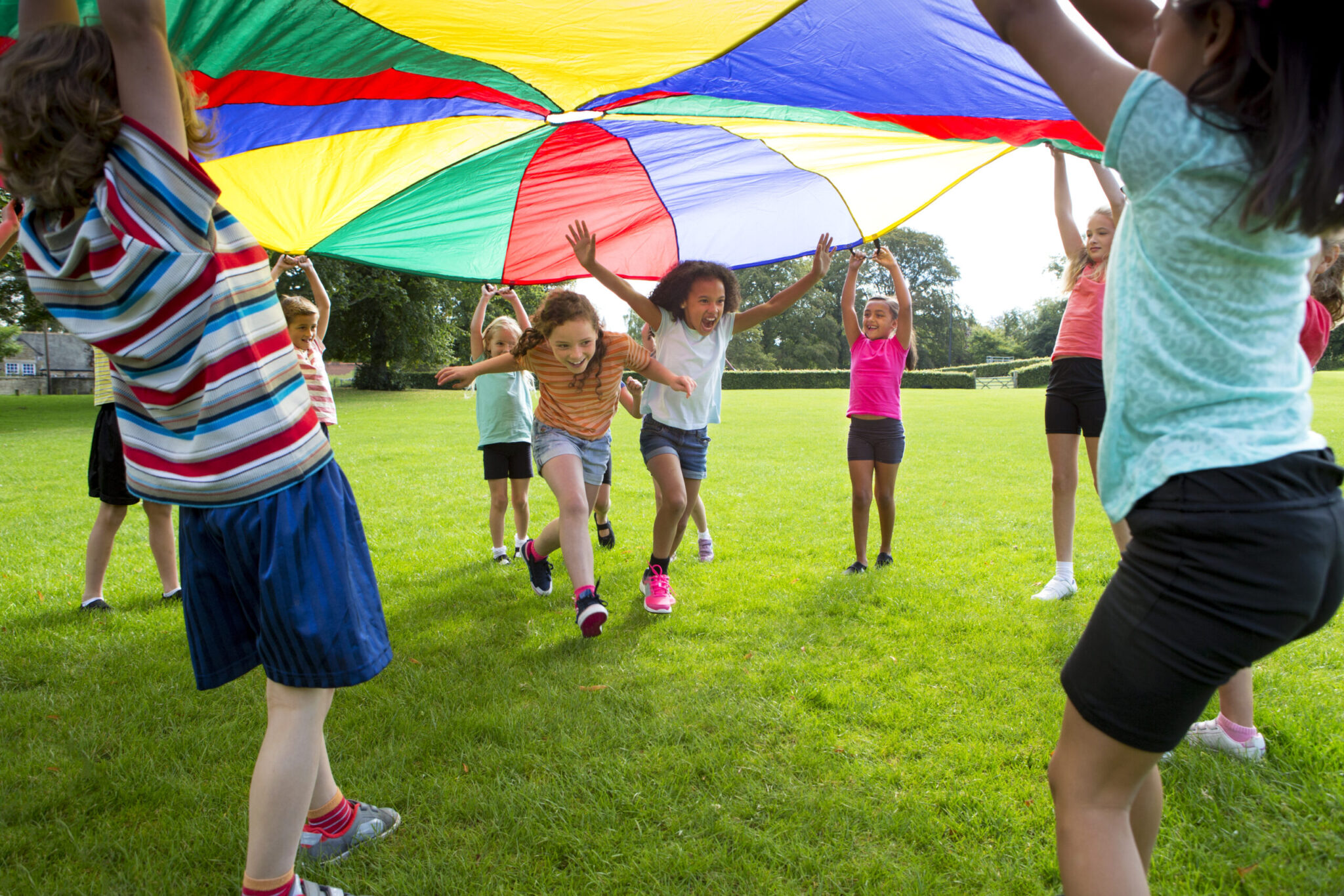 Children playing a game with a colourful Parachute